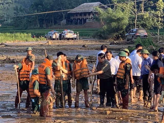 Prime Minister Phạm Minh Chính (4th right) visits a search and rescue team for victims of flash floods and landslides in Nủ Village.