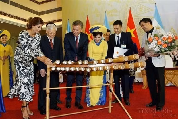 Argentine President Mauricio Macri tries his hand at playing a Vietnamese traditional music instrument during his Việt Nam visit in 2019. — VNA/VNS File Photo