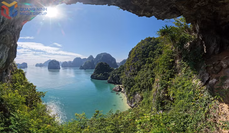 The cave entrance at Ba Cat embraces the shimmering bay under sunlight, highlighting the undulating limestone islets.