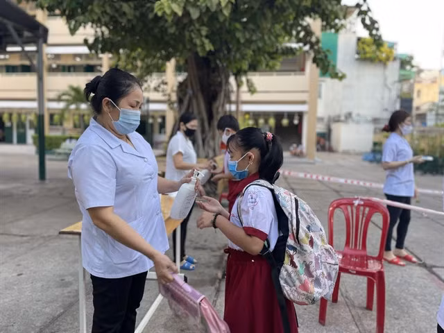 Disinfecting hands for students before entering class at a primary school in HCM City.