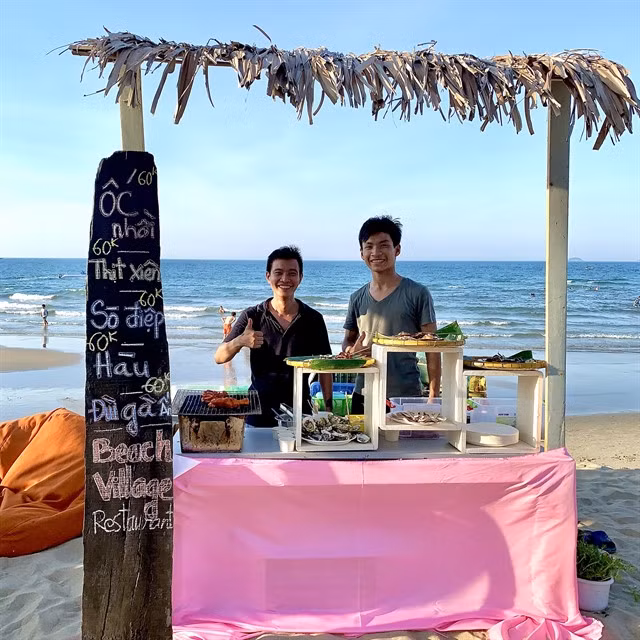 Two servers introduce authentic seafood at An Bàng beach. Photo courtesy of An Bàng beach village restaurant