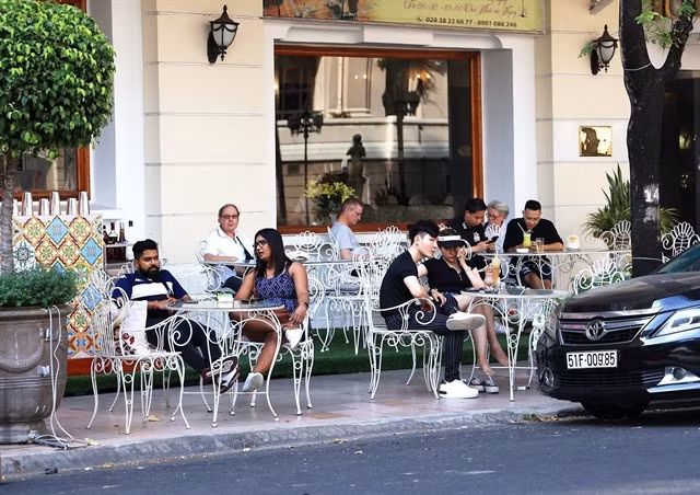 Foreign tourists enjoy coffee in the front of the Continental Hotel in HCM City. — VNA/VNS Photo Hồng Đạt