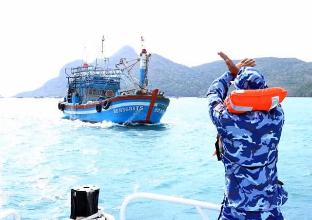 A coast guard officer signals a fishing vessel to stop for inspection of compliance with regulations against illegal, unreported and unregulated (IUU) fishing. VNA/VNS Photo An Đăng