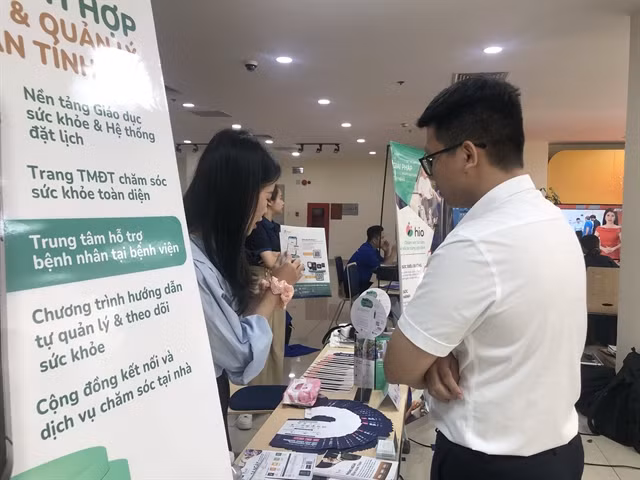 An employee introduces her company’s healthcare solution to a visitor. — VNS Photo