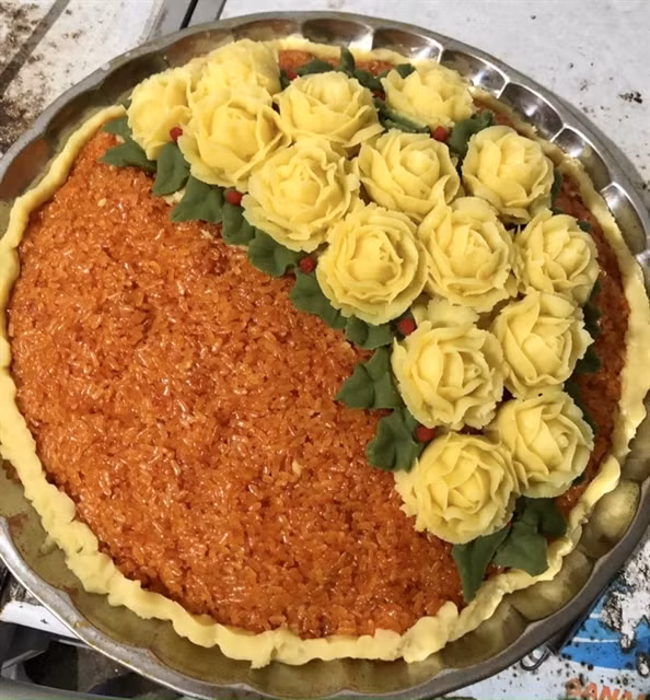 A tray of sticky rice with spiny gourd (xôi gấc) decorated with roses made from green bean is among many different sticky rice dishes recently displayed at Phú Thượng traditional craft of cooking sticky rice festival. — Photo daibieunhandan.vn