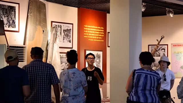 Guide Hà Minh Triết (fourth from right) explains the fighting tactics of Vietnamese people's Army during the American War in Việt Nam to visitors. VNS Photo Nhật Hồng